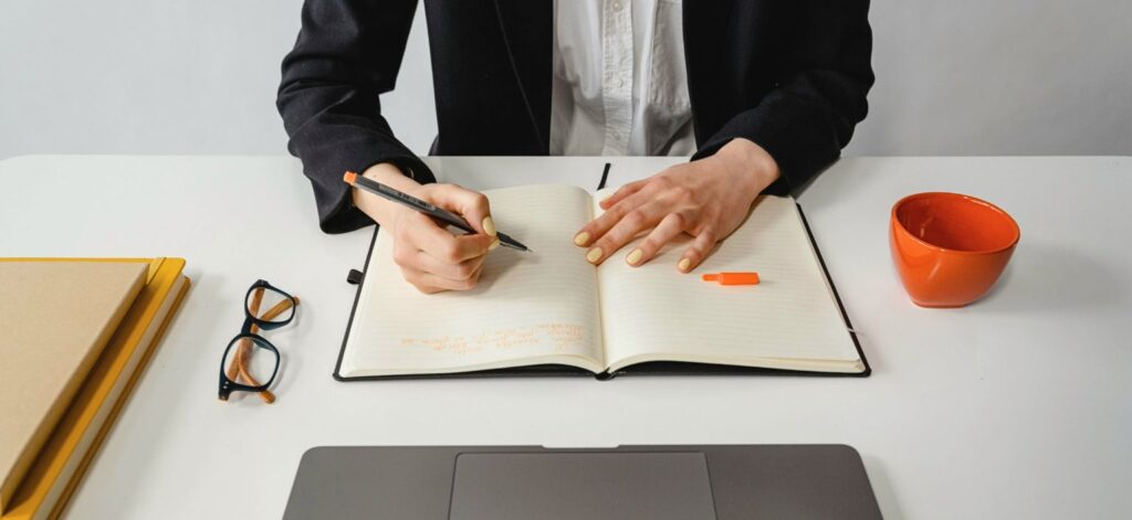 A person writing notes at an organized desk